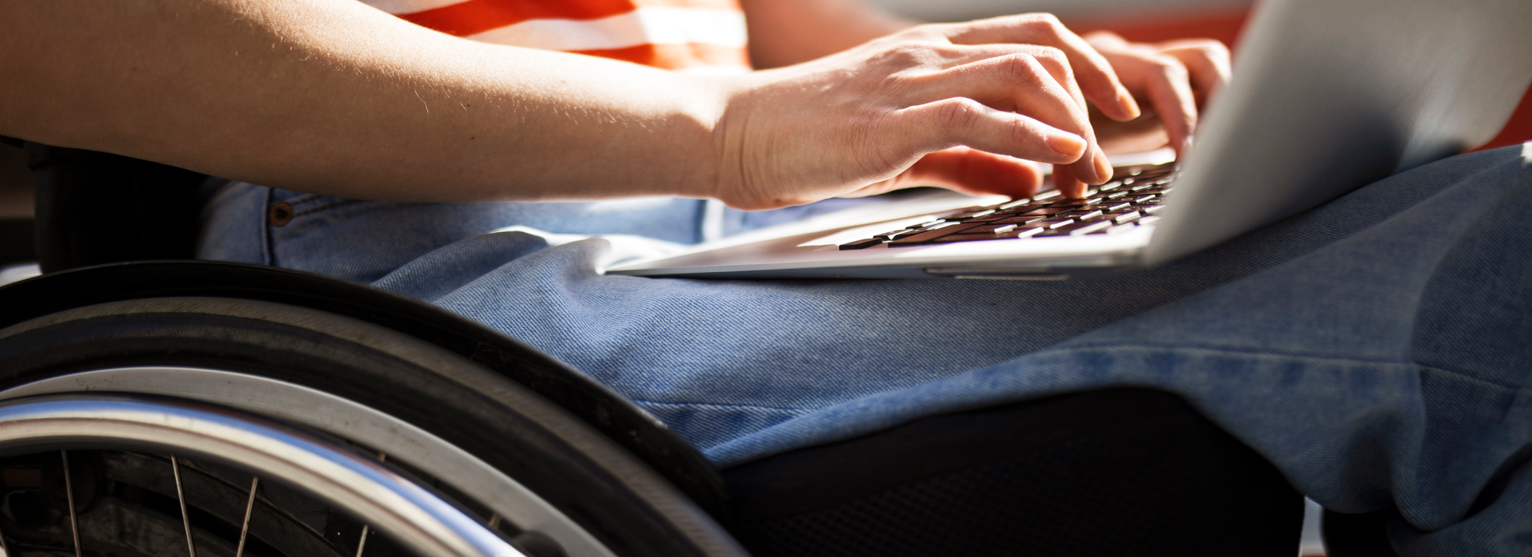 A person in a wheelchair focused on using a laptop, highlighting digital accessibility and inclusion in technology.
