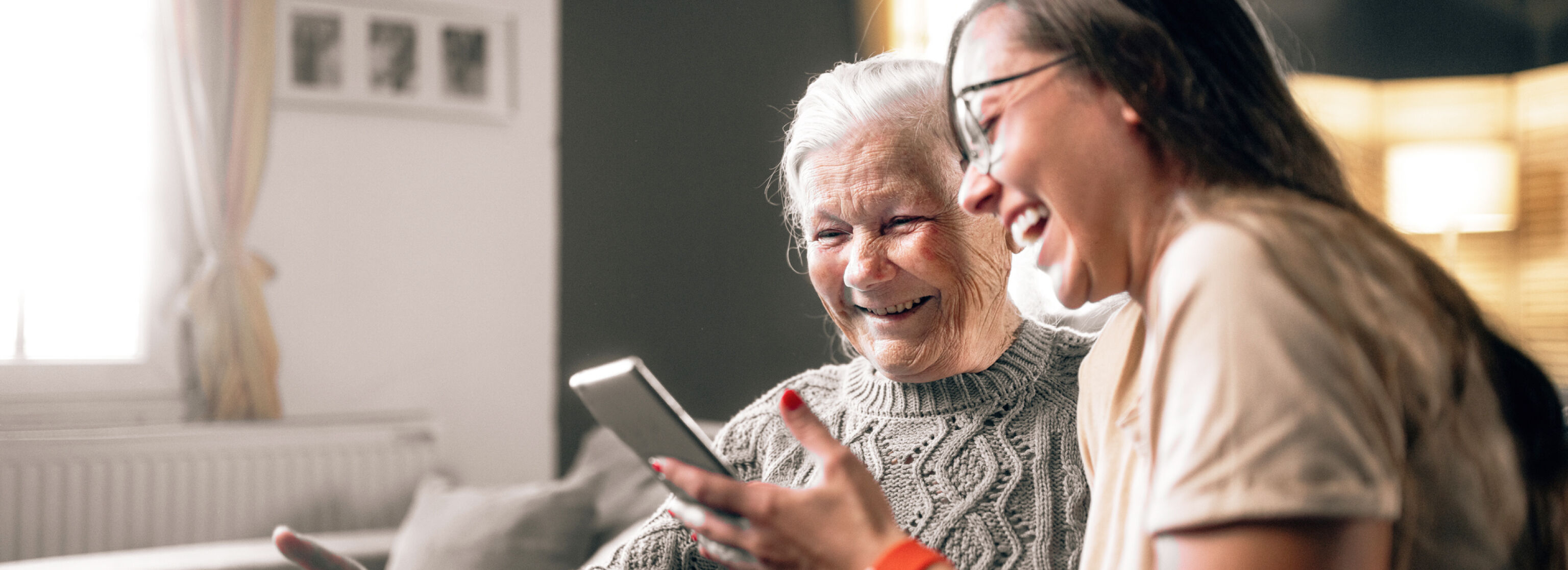 Granddaughter and grandmother using a mobile phone at home.